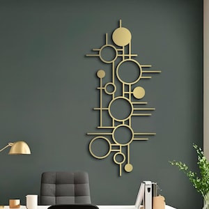 Op de afbeelding: Een modern kantoor met een witte bureau, zwarte stoel en gouden accenten. Een gouden geometrisch kunstwerk hangt aan een donkergroene muur. Een gouden bureaulamp en een potplant vullen de inrichting aan.
