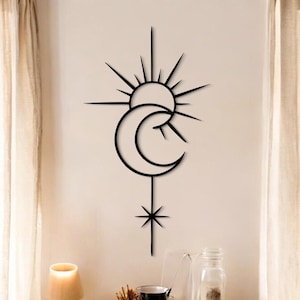 May include: Black metal wall art depicting a sun, crescent moon, and star. The celestial design is mounted on a neutral wall. This decorative piece adds a touch of modern and bohemian style to any room. The artwork is a striking contrast.