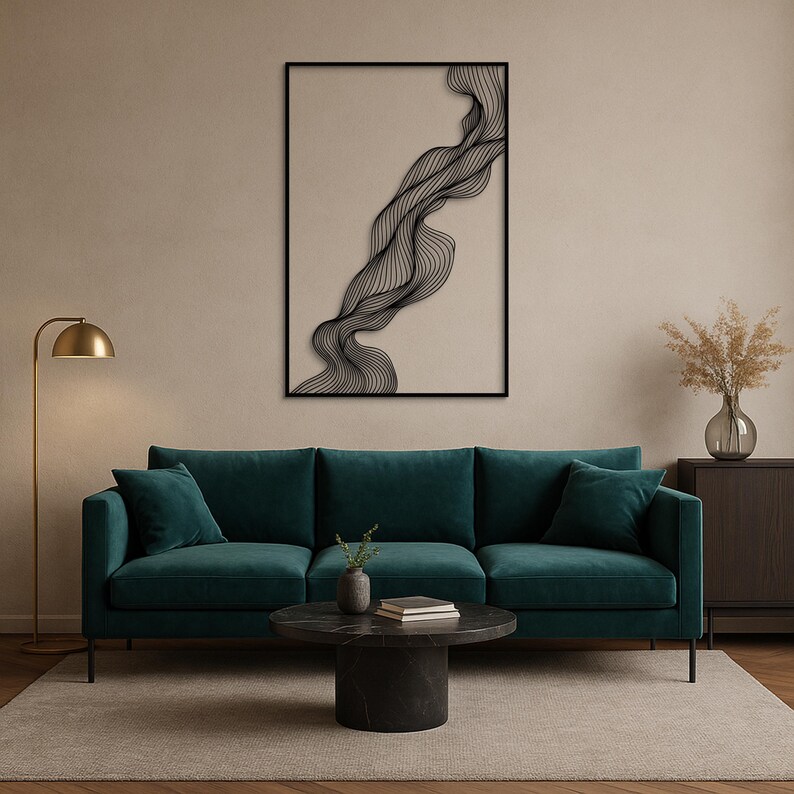 May include: A modern living room featuring a teal sofa, a black marble coffee table, and a framed abstract wall art. The artwork has a black, wavy line design against a beige background. A gold floor lamp and a vase with dried flowers complete the decor.