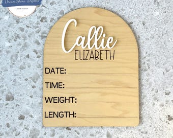 May include: A wooden arch-shaped sign with the name "Callie Elizabeth" in white lettering. The sign has spaces to write the date, time, weight, and length.