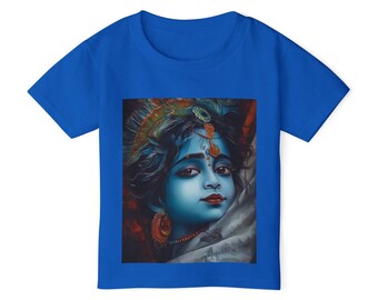 May include: A vibrant royal blue t-shirt displaying a detailed portrait of a figure with blue skin, adorned with elaborate headwear and jewellery. The artwork features a calm expression and intricate details, set against a soft, blurred background.