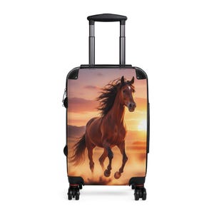May include: A rolling suitcase featuring a graphic print of a brown horse galloping across a field during a sunset. The luggage has a black frame, a retractable handle, and four wheels at the base, providing a functional design for travel.