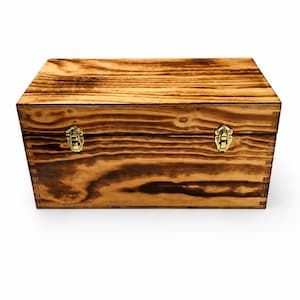 Può includere: Una scatola di legno rettangolare con finitura a venature naturali. La scatola ha un coperchio incernierato ed è assicurata con due chiusure color ottone. Il legno ha un tono marrone caldo con accenti più scuri e bruciati.