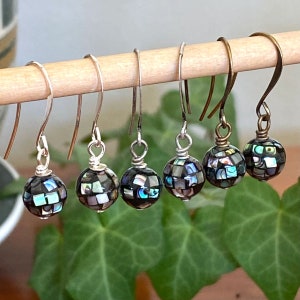 May include: Five pairs of silver dangle earrings with iridescent black and green abalone shell bead drops.