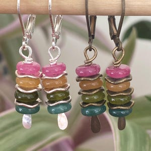 May include: Four pairs of colorful beaded earrings. Each earring features a stack of round, colorful beads in shades of pink, yellow, green, and teal. The earrings are suspended from silver or bronze-toned ear wires.