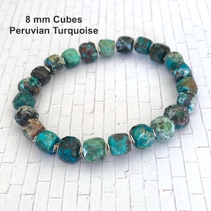 May include: A bracelet made with 8 mm turquoise cubes. The turquoise is a mix of blue, green, and brown colors. The bracelet is strung on silver wire.