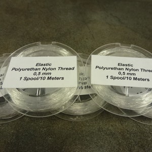 May include: Five spools of clear elastic polyurethane nylon thread, each spool labeled "Elastic Polyurethan Nylon Thread 0,5 mm 1 Spool/10 Meters".