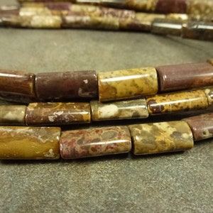 May include: A strand of brown, red, and white jasper beads. The beads are cylindrical and have a mottled appearance.