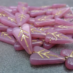 May include: A pile of pink glass heart-shaped beads with gold leaf accents. The beads have a tree-like design on them.