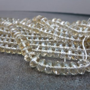 May include: A strand of faceted, translucent, light brown gemstone beads. The beads are round and have a slightly irregular shape.