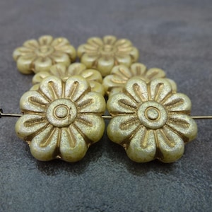 May include: Six off-white glass flower beads with gold accents. The beads are strung on a wire.