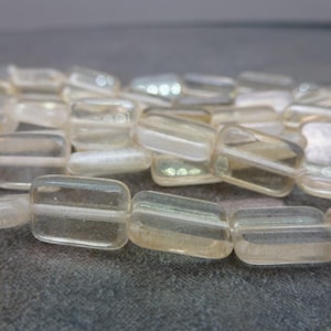 May include: A strand of translucent, light brown, rectangular glass beads. The beads are smooth and have a slight shimmer.