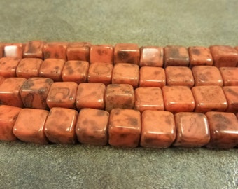 May include: A strand of orange and brown square-shaped beads. The beads have a mottled, marbled appearance.