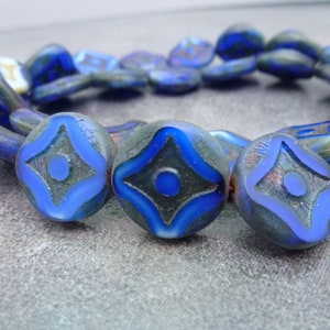 May include: A strand of blue glass beads with a starburst design. The beads are iridescent and have a textured surface.