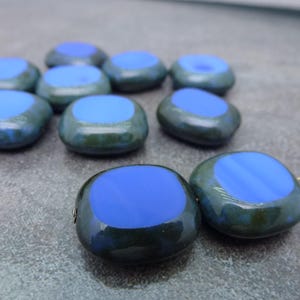 May include: A group of ten blue and green glass beads with a smooth, rounded shape. The beads have a dark green outer layer with a light blue center.