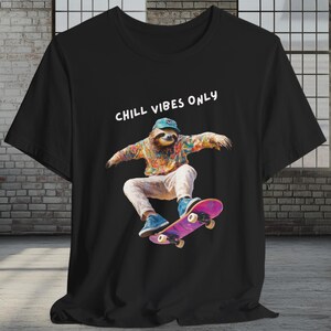 May include: Black t-shirt featuring a colorful graphic of a sloth skateboarding. The sloth wears a hat and colorful clothing. The text "CHILL VIBES ONLY" is above the sloth. The skateboard is pink and purple.