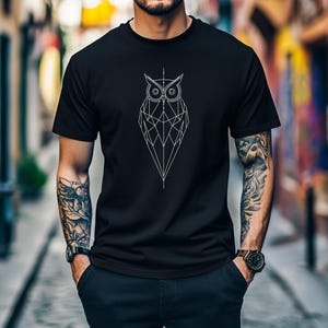 Puede incluir: Una camiseta negra con un diseño de búho geométrico blanco.