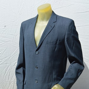 May include: A dark blue blazer with a three-button fastening. The blazer has a textured fabric and a classic fit.