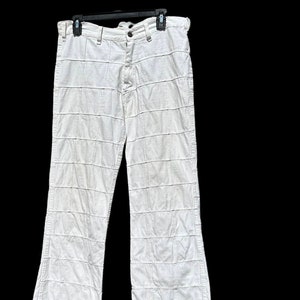 May include: White wide-leg pants with a unique patchwork design. The pants are made of a lightweight fabric and have a relaxed fit.