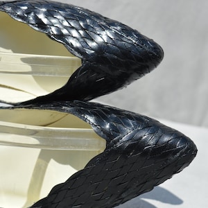 Pu&ograve; includere: Un paio di scarpe nere in pelle intrecciata con punta a punta e tacco basso.