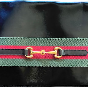 May include: Black patent leather clutch with a green, red and black striped band and a gold horse bit closure.