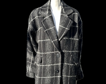 May include: A black and white plaid blazer with a classic notched collar and two front pockets. The blazer has a two-button closure and is displayed on a mannequin. The pattern is a large grid of white lines on a black background.