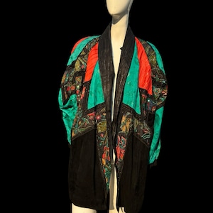 May include: A long black and turquoise jacket with colorful embroidery and sequins. The jacket has a wide collar and a long, flowing silhouette.