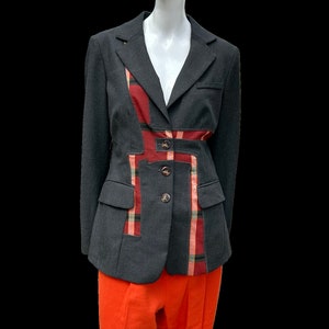 Peut inclure: Un blazer gris foncé avec un motif à carreaux sur le devant et les côtés. Le blazer a une fermeture à bouton unique et deux poches. Le blazer est porté par un mannequin.