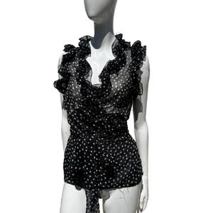 May include: Black and white polka dot top with a ruffled neckline and a wrap-style design. The sleeveless blouse features a tie detail at the waist and is displayed on a mannequin. The top is made of a sheer fabric.