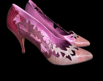 May include: A pair of pink high-heeled shoes with cutouts and a snakeskin pattern.