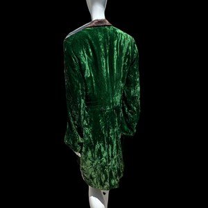K&ouml;nnte beinhalten: Eine gr&uuml;ne Samtjacke mit schwarzem Kragen und einem einzigen Knopfverschluss. Die Jacke befindet sich auf einem wei&szlig;en Mannequin.