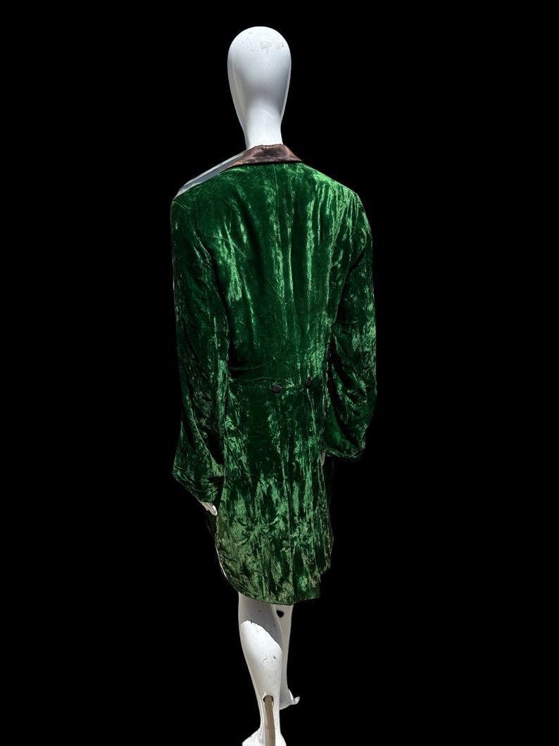 K&ouml;nnte beinhalten: Eine gr&uuml;ne Samtjacke mit schwarzem Kragen und einem einzigen Knopfverschluss. Die Jacke befindet sich auf einem wei&szlig;en Mannequin.