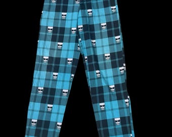 Könnte beinhalten: Blau karierte Hose mit einem sich wiederholenden Muster aus weißen Totenkopf-Grafiken mit Sonnenbrille. Die Hose hat ein klassisches Fünf-Taschen-Design und einen Knopf- und Reißverschluss. Das Karomuster ist in Blau- und Schwarztönen gehalten.