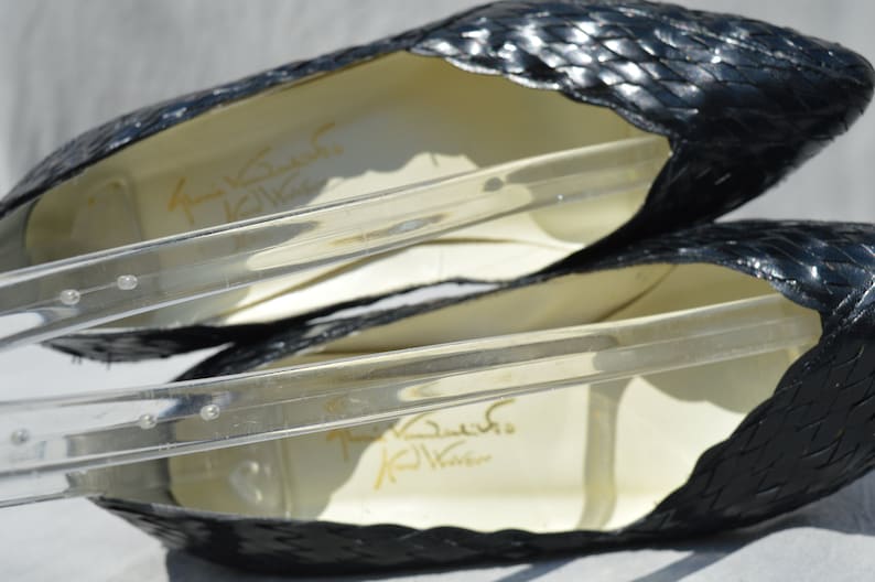 Pu&ograve; includere: Un paio di scarpe nere in pelle intrecciata con punta a punta. Le scarpe hanno una fodera in pelle bianca e il nome del marchio "Karl Lagerfeld" &egrave; stampato all'interno.