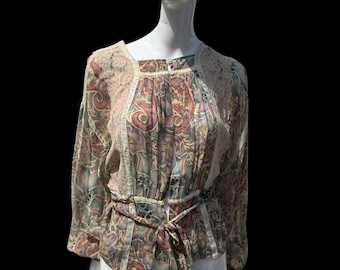 May include: A vintage-style blouse with a floral pattern in shades of pink, green, and beige. The blouse features long sleeves, a tie-waist, and lace detailing around the neckline and shoulders. The garment is displayed on a mannequin.