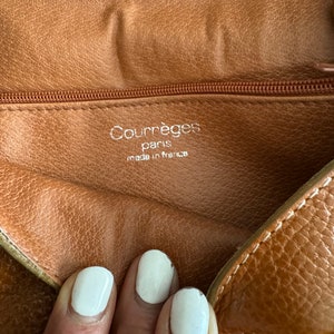 Puede incluir: Primer plano del interior de un bolso de cuero marr&oacute;n con cremallera. La etiqueta dice "Courr&egrave;ges Paris made in France".