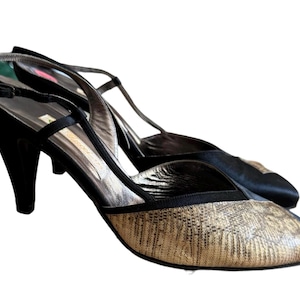 May include: Black and gold heeled slingback shoes with a patterned design on the toe.