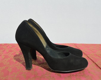 May include: A pair of black suede high-heeled pumps with a closed toe.