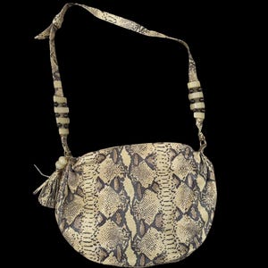 Könnte beinhalten: Eine Handtasche mit Schlangenmuster in Beige und Braun, mit einem langen Riemen. Der Riemen hat das gleiche Muster wie die Tasche und ist mit dekorativen Perlen versehen. Eine kleine Quaste hängt an der Seite. Der Hintergrund ist schwarz.