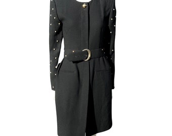 May include: A black belted dress with gold stud detailing on the sleeves. The dress has a simple, classic design and a fitted silhouette.