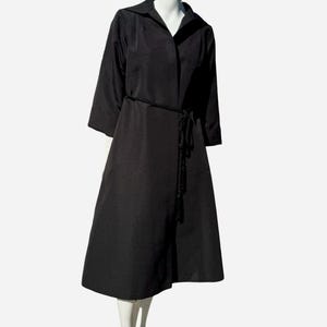 May include: A black, long-sleeved dress with a collared neckline and a rope belt. The dress has a slightly flared skirt and a relaxed fit.