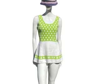 May include: A green and white polka dot swimsuit with a white skirt and green trim. The swimsuit is on a white mannequin wearing a striped hat.