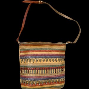 May include: A colorful, striped shoulder bag with a long strap. The bag features horizontal bands of various colors, including red, yellow, green, and blue. The strap is a lighter color than the bag. The bag has a unique, textured appearance.