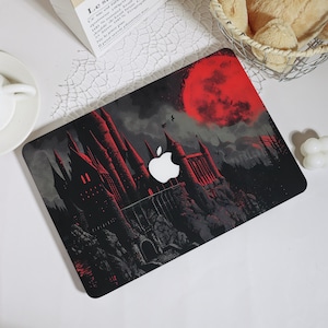 May include: A laptop skin featuring a dark, gothic castle illustration set against a vibrant red moon and black sky. The design incorporates the white Apple logo in the center, surrounded by detailed spires and rocky terrain in shades of black, gray, and deep red.