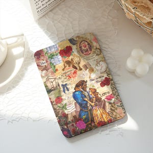 May include: A rectangular e-reader case featuring a collage design with Beauty and the Beast characters, red roses, vintage-style frames, and script text. The artwork includes the Beast in a blue coat and Belle in a yellow dress, surrounded by floral patterns and decorative elements in shades of gold, red, and blue.
