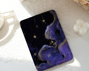 Könnte beinhalten: Eine rechteckige Handyhülle mit einem Himmelsdesign. Die Hülle hat einen dunkelblauen Hintergrund mit wirbelnden lila und goldenen Akzenten und goldenen Sterndetails. Das Design erinnert an ein Nachthimmel-Thema.