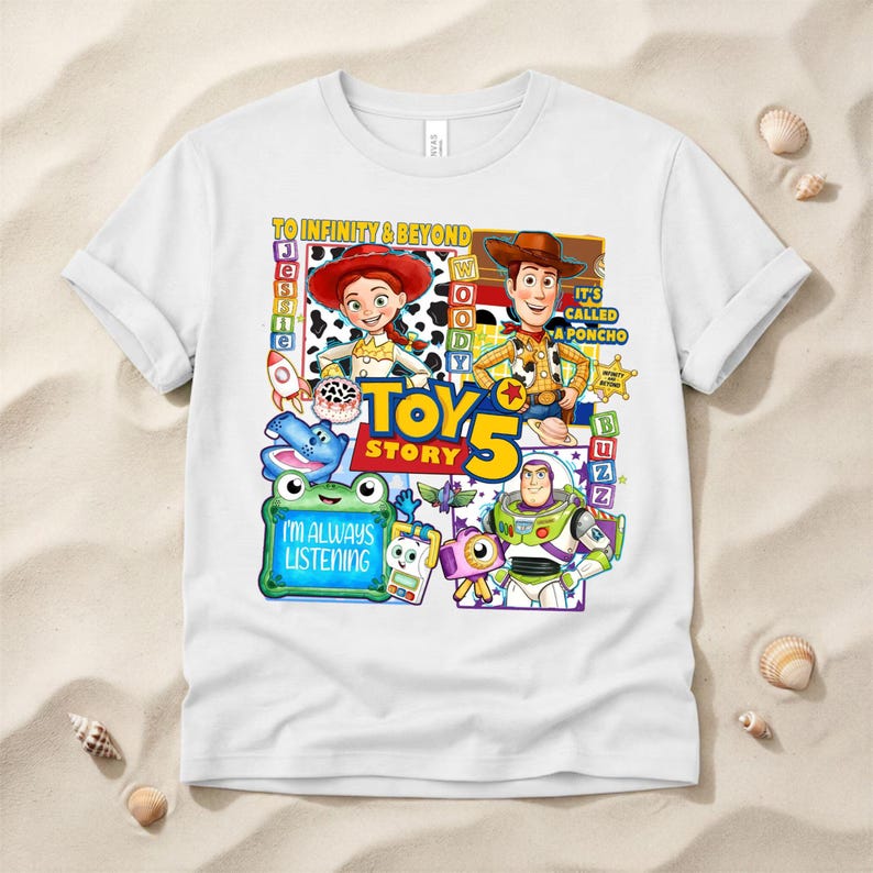 May include: A white short-sleeved t-shirt featuring a colorful graphic print of Toy Story characters including Jessie, Woody, and Buzz Lightyear. The design includes the text TO INFINITY & BEYOND, TOY STORY 5, IT'S CALLED A PONCHO, and I'M ALWAYS LISTENING.
