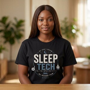 Peut inclure: T-shirt noir avec l'inscription "SLEEP TECH" en blanc et bleu clair, accompagnée de graphiques médicaux. Le texte "WE DON'T DREAM - WE RECORD THEM - RPSGT-" est également imprimé sur le t-shirt.