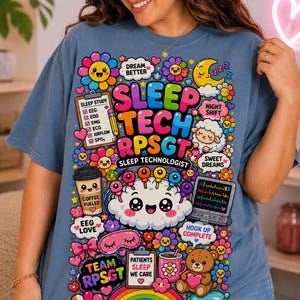 Peut inclure: Un t-shirt bleu avec une impression graphique colorée portant le texte SLEEP TECH RPSGT SLEEP TECHNOLOGIST. Le motif comprend des illustrations d'un presse-papiers, d'une tasse de café, d'un écran, d'un ours en peluche, de fleurs et d'un nuage.