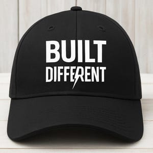 May include: Black baseball cap with white text that reads "BUILT DIFFERENT" with a lightning bolt graphic.